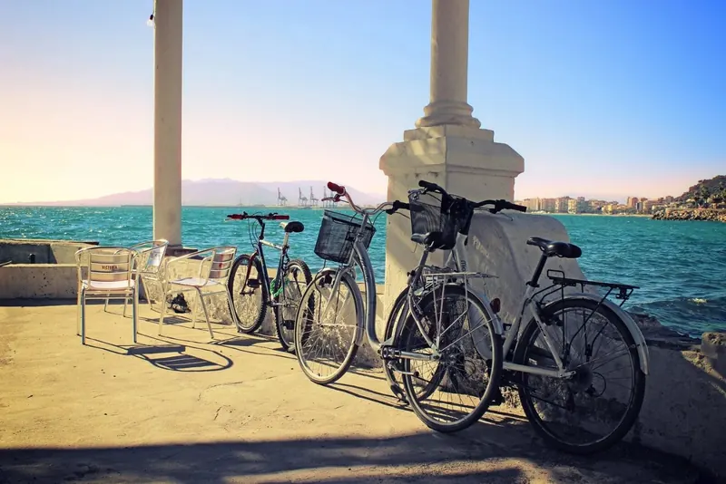 Bicycles parked on the seafront promenade in Málaga with the port in the background